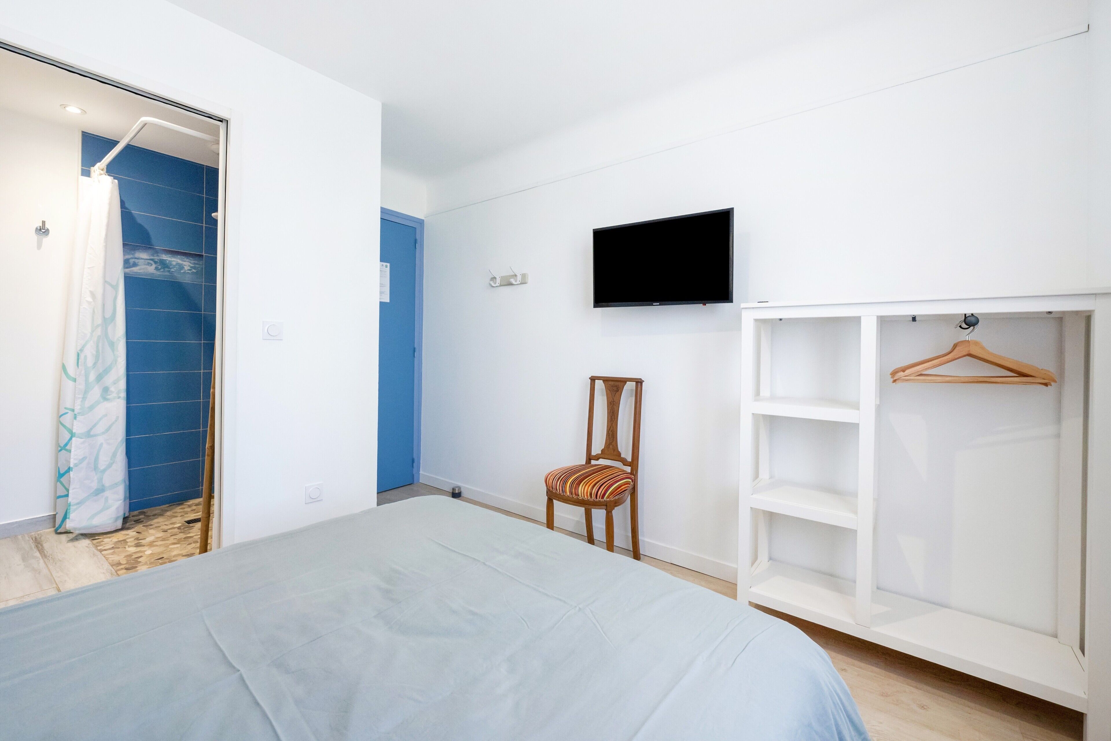 Een slaapkamer met een bed, een televisie, een kledingkast en een stoel.
