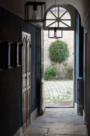 A hallway with a dark wall, a wooden door, and a hanging light fixture.
