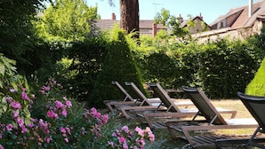 Un jardín con sillones de madera y flores florecientes.