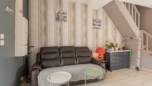 Ein Wohnzimmer mit einer Ledersofa, einem kleinen Tisch, einer Kommode mit Dekoration und einer Treppe.