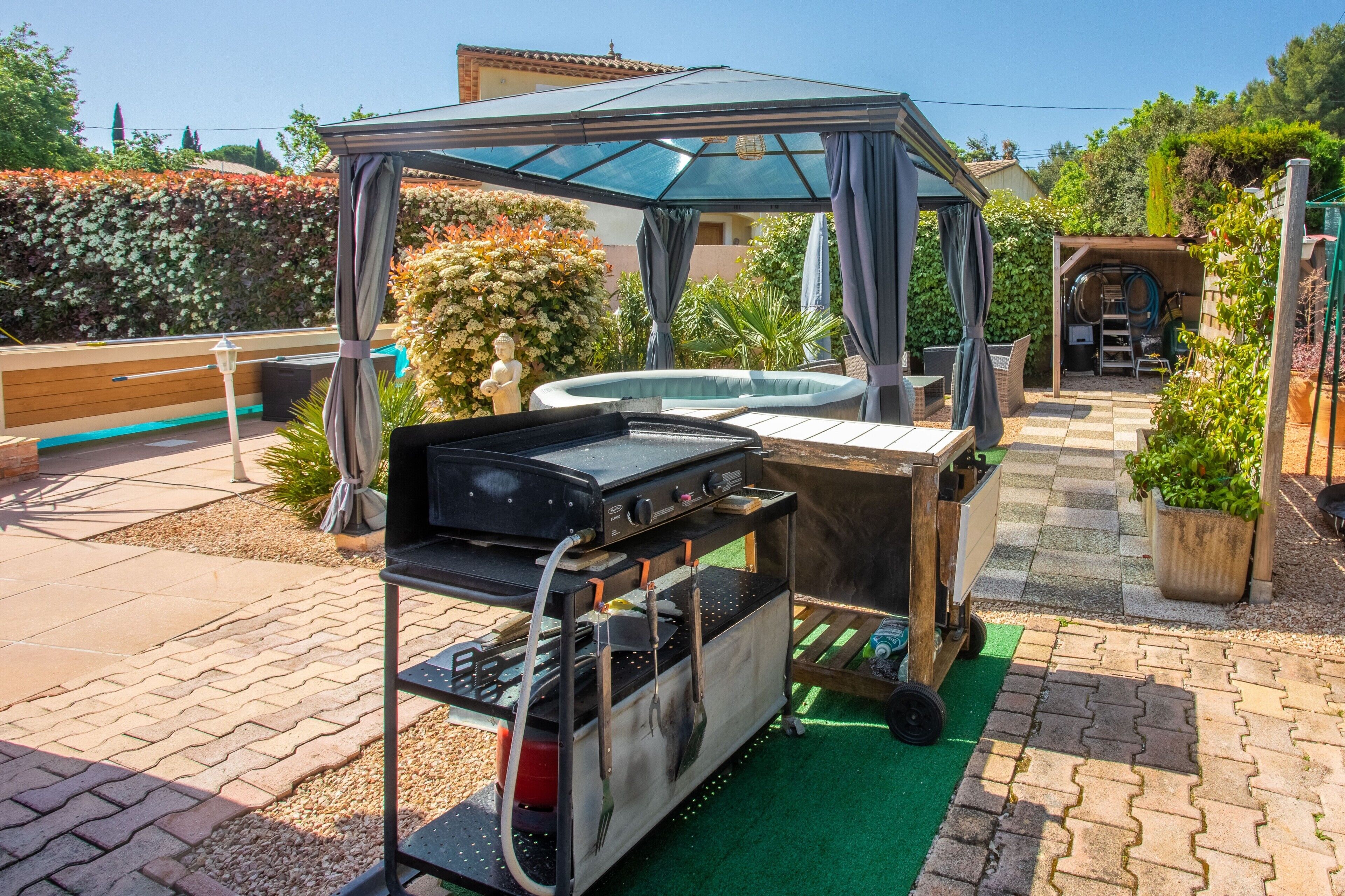 A patio area with a grill, a covered seating area, and a small hot tub.