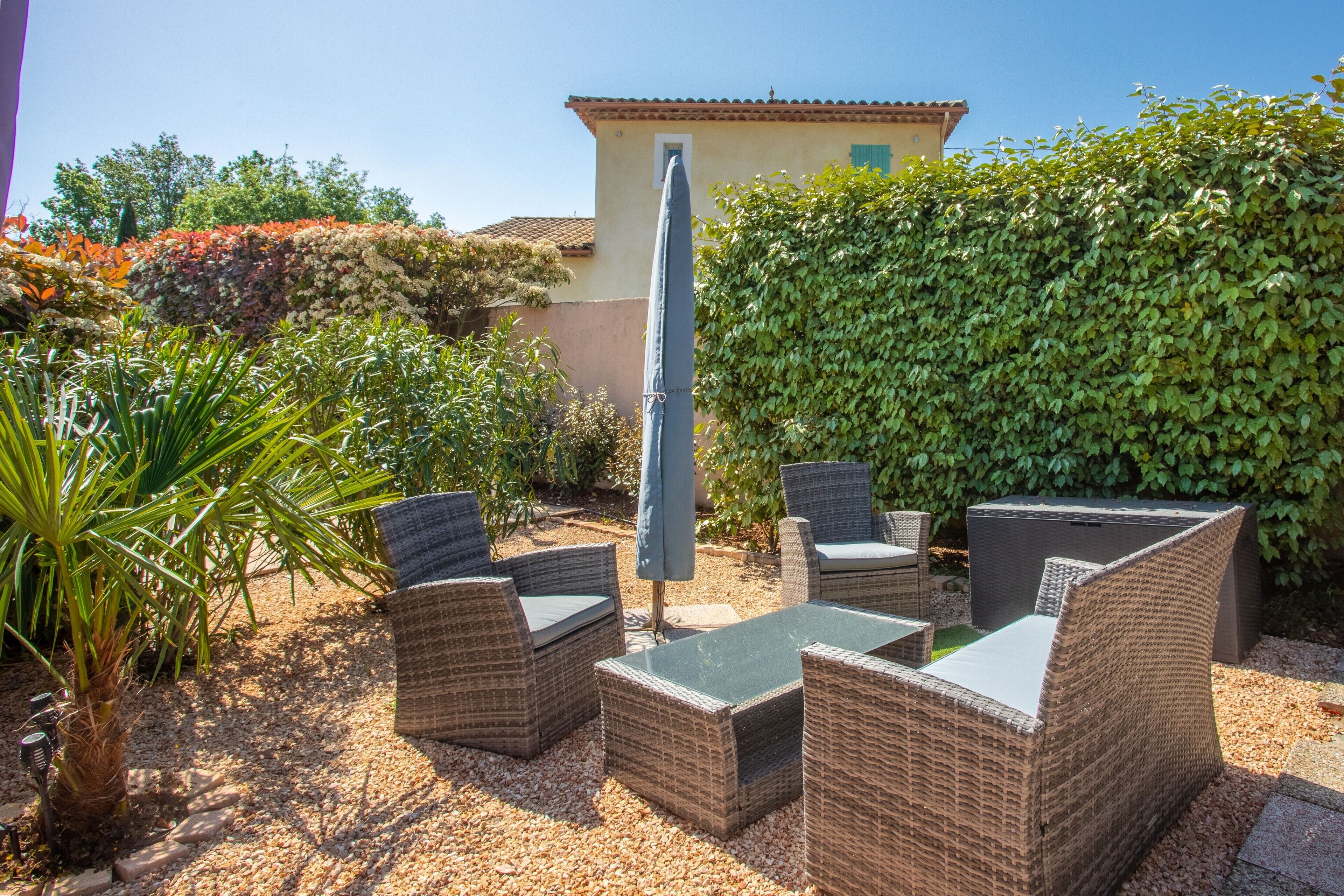 An outdoor patio with wicker furniture, a table, and an umbrella.