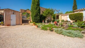 A courtyard with a gravel path, a white door, a tall cypress tree, and a variety of potted plants and flowers. - Guest Room "Chrisama" with Shared Pool, Wi-Fi, and Air Conditioning (Flayosc)