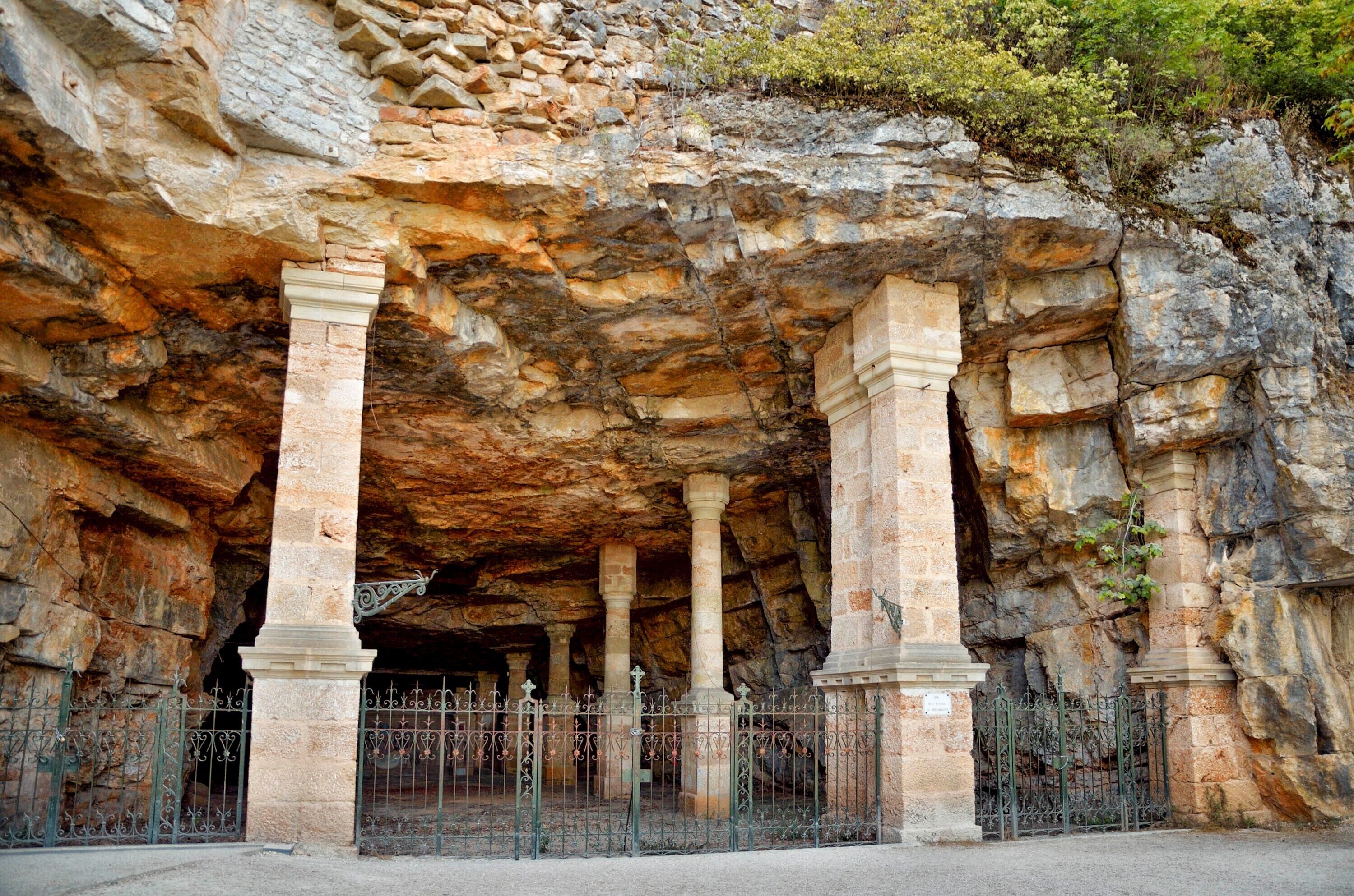 L’entrée d’une grotte, avec des colonnes et une clôture en métal.