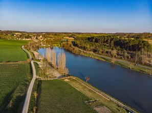 Een rivier met een brug, omgeven door velden en bomen.