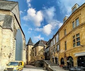 Een smalle straat met historische gebouwen van steen, een brug en terrasjes.