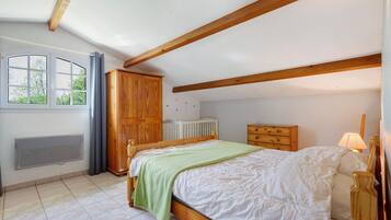 Een slaapkamer met een bed, een houten garderobe, een radiator en een raam met gordijnen.