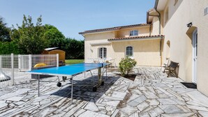 A courtyard with a ping pong table, outdoor seating, and a building with a tiled roof. - Spacious House in the Heart of Médoc Between Estuary and Ocean (Bégadan)