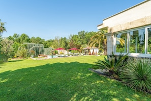 A well-maintained garden with a pool, outdoor seating, and a large windowed structure. - L'Oasis de Boisset: 5-Star Mas with Private Pool, Spa & Sauna (Boisset-et-Gaujac)