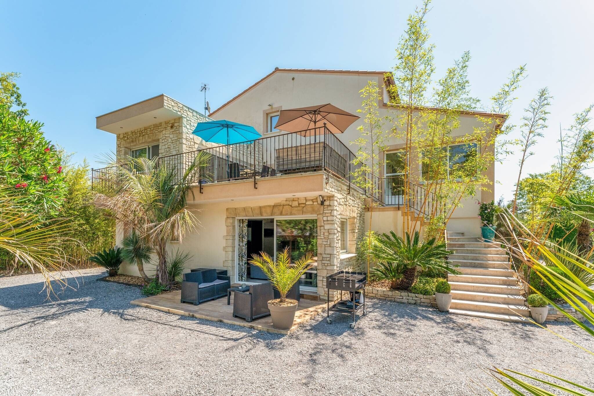 A two-story house with a balcony, outdoor seating, and a barbecue area.
