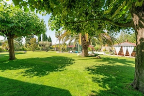 A lush garden with a gazebo, palm trees, and a well-maintained lawn. - L'Oasis de Boisset: 5-Star Mas with Private Pool, Spa & Sauna (Boisset-et-Gaujac)