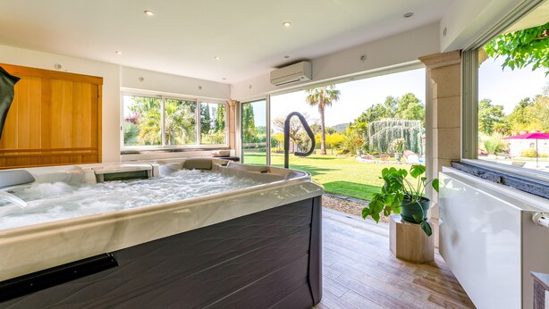 Une salle de bain moderne avec une grande baignoire, un meuble en bois et une vue sur un jardin.