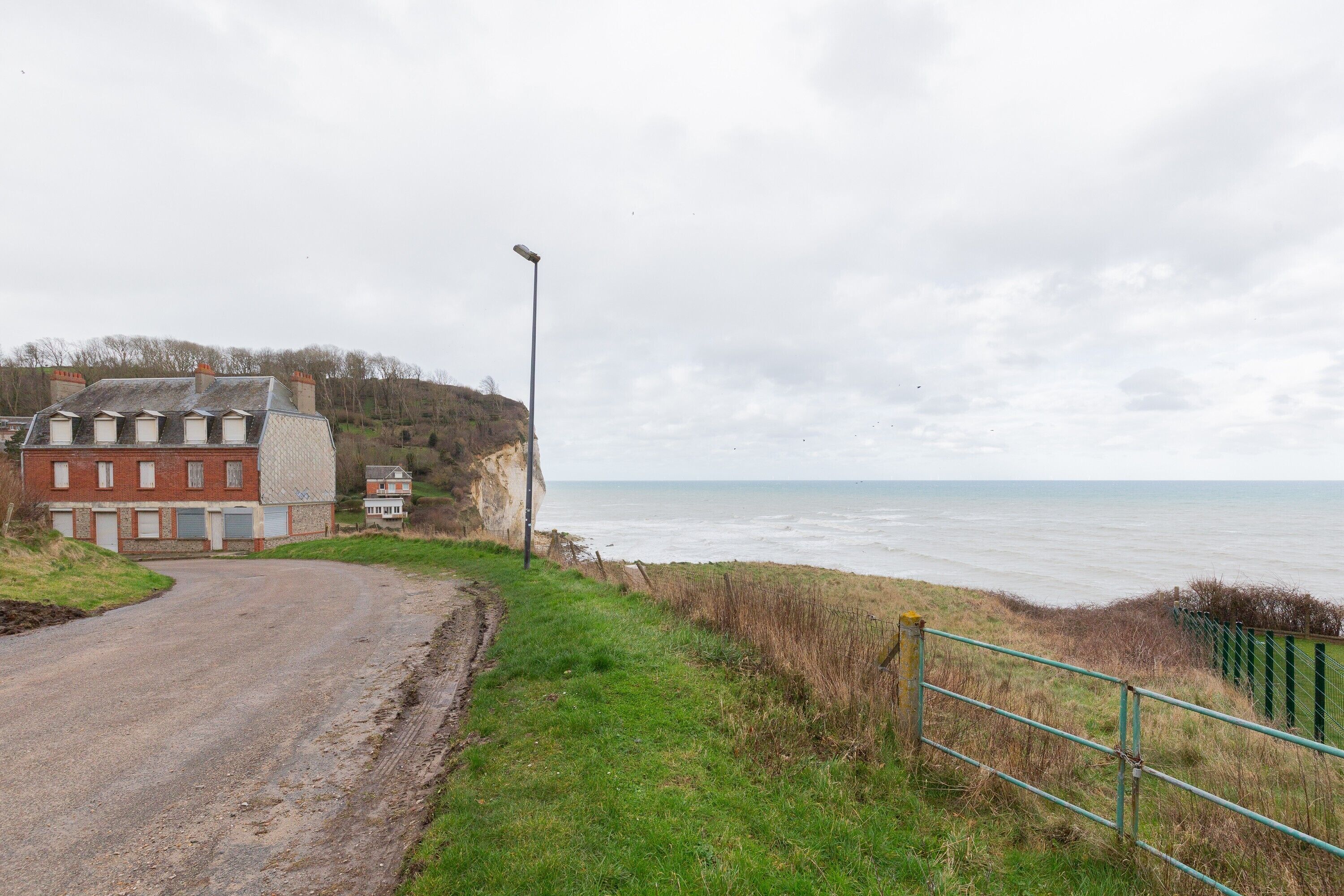 Uma estrada costeira que leva a um edifício com vista para o mar.