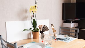 Een eettafel met een plant, een ventilator en een bord met bestek.