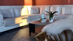 Un salon moderne avec un canapé, une table basse, un fauteuil et une plante en pot.