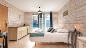 Una habitación con cama, escritorio, silla, armario y vistas a través de un ventanal.