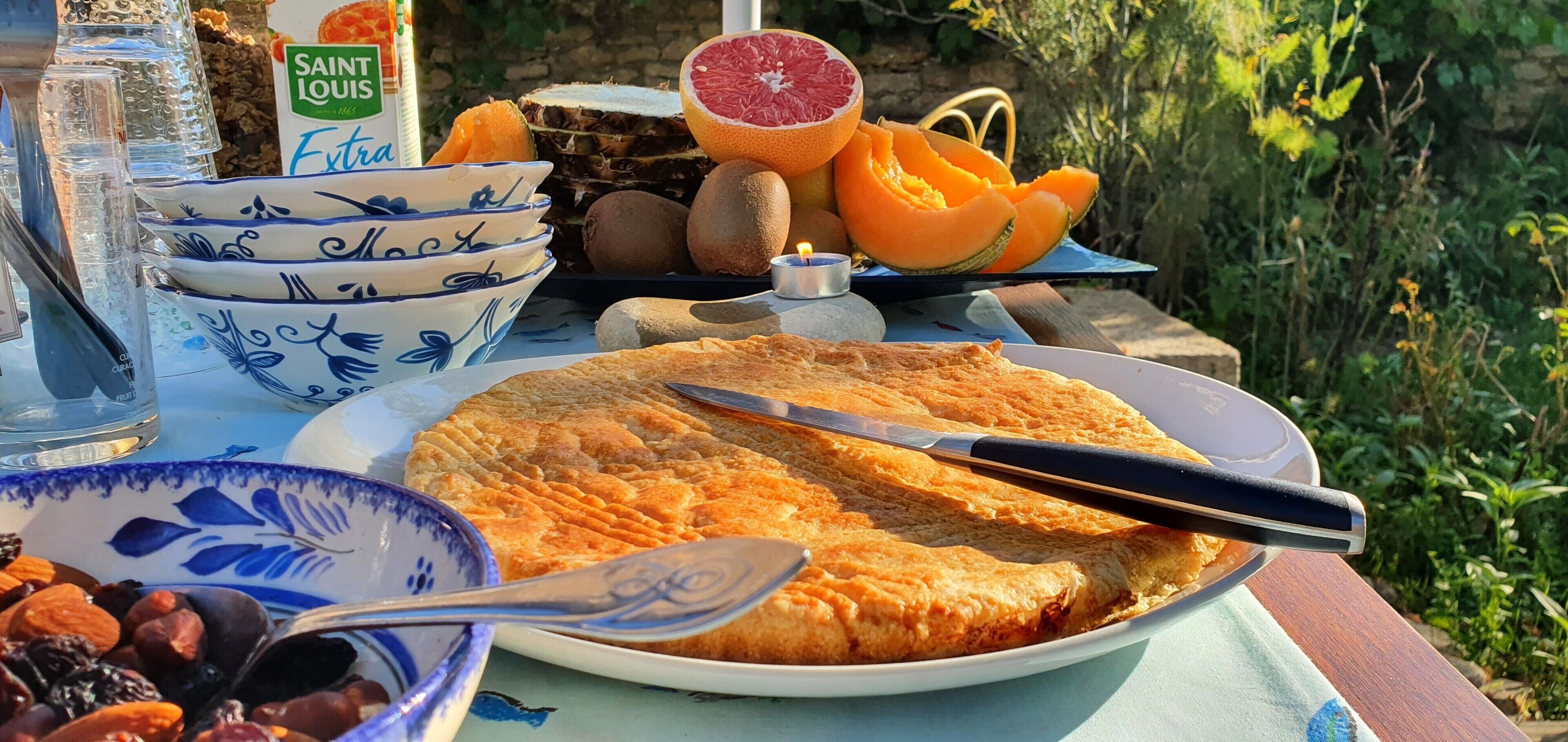 Une table avec une tarte, des bols, une bouteille et des fruits.