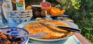 Una mesa con tarta, cuencos, una botella y frutas.