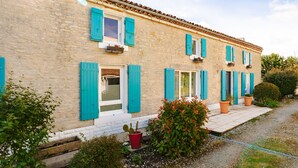 A two-story building with a stone facade, blue shutters, and potted plants. - Guest Rooms - Aubépine and Bleuet Rooms (Courçon)