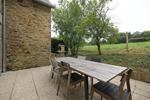 A stone building with a wooden table and chairs outside. - Domaine de la Dauvinerie – Escapade Cottage (Gratot)