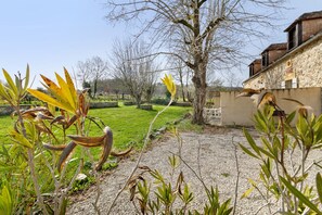 Un jardín con plantas y un edificio de paredes de piedra.