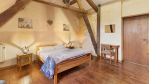 A bedroom with a wooden bed, a nightstand, a small table, and a door.