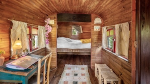 A wooden cabin interior with a bed, a desk with a lamp, and a chair. - Bed and Breakfast 'Espace Roulotte - Les Toits Du Gaou' with Shared Terrace and Wi-Fi (Six-Fours-les-Plages)