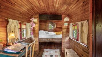 L’intérieur d’une cabane en bois, avec un lit, un bureau doté d’une lampe et une chaise.