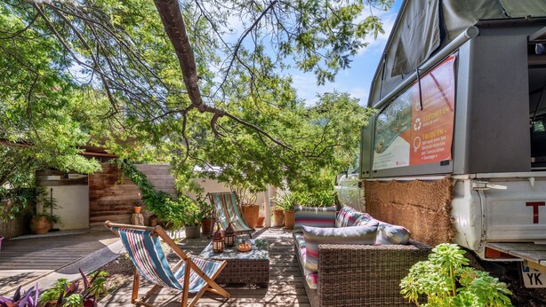 An outdoor patio with wicker furniture, a striped chair, and potted plants. - Bed and Breakfast 'Espace Roulotte - Les Toits Du Gaou' with Shared Terrace and Wi-Fi (Six-Fours-les-Plages)