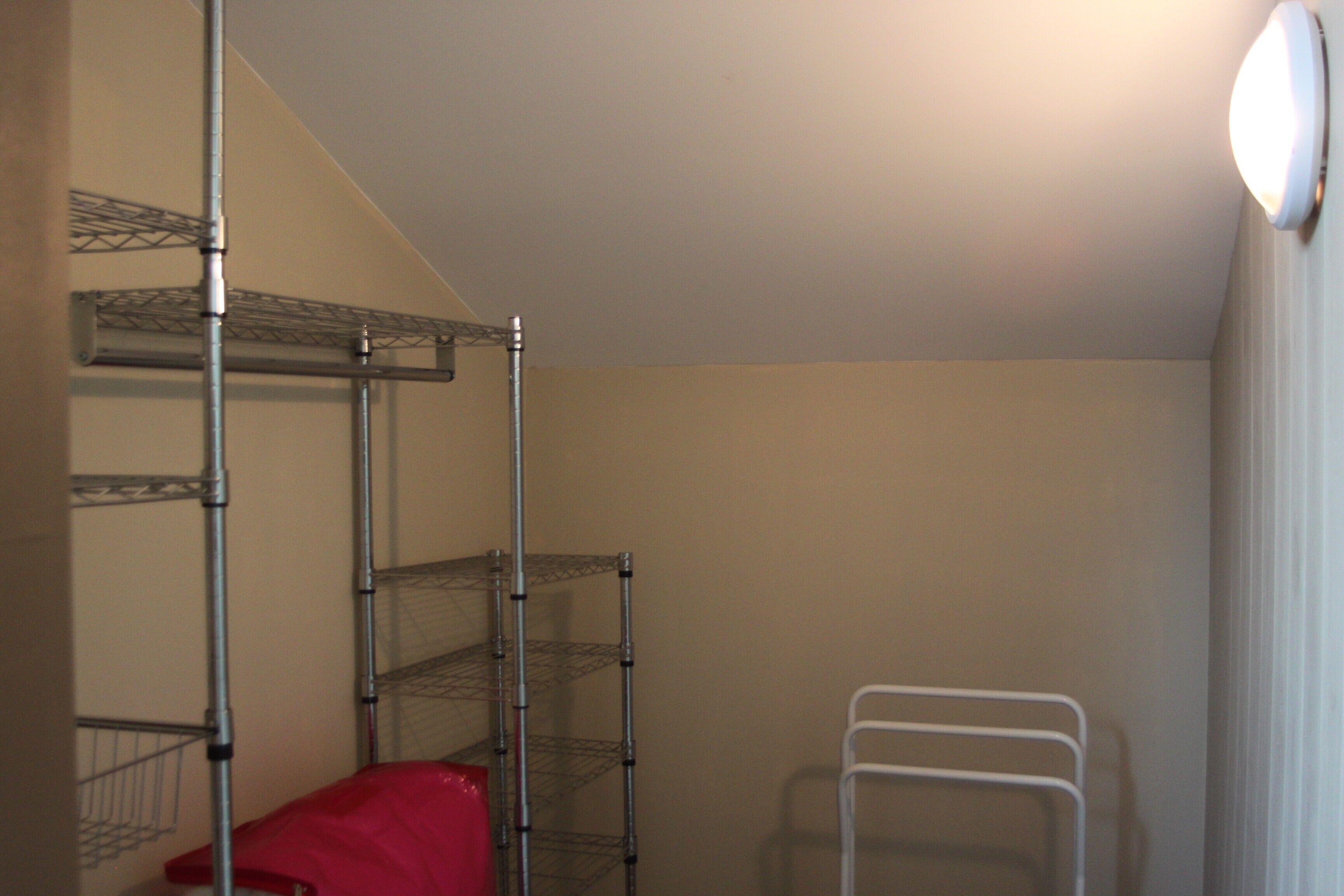 A room with metal shelving units, a red chair, and a white chair.