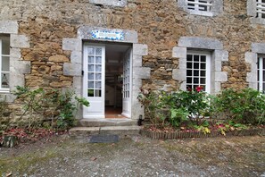 Ein Steinhaus mit einem Schild, auf dem 'Gîte ELOUENT' steht, und einer Tür, die nach innen führt.