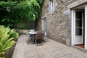 Ein Steinhaus mit Terrasse, Tisch und Stühlen sowie einer Tür.