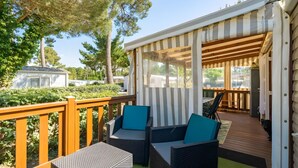 A covered outdoor seating area with wicker furniture and a view of the surrounding greenery. - Mobile Home 'Mh324 La Tremblade' with Shared Pool, Private Terrace, and Air Conditioning (La Tremblade)