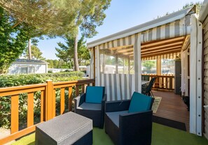 Un espace extérieur abrité, aménagé avec des meubles en osier et offrant une vue sur la verdure environnante.