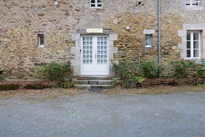 Un bâtiment en pierre avec une porte blanche, de petites fenêtres et une enseigne au-dessus de la porte.