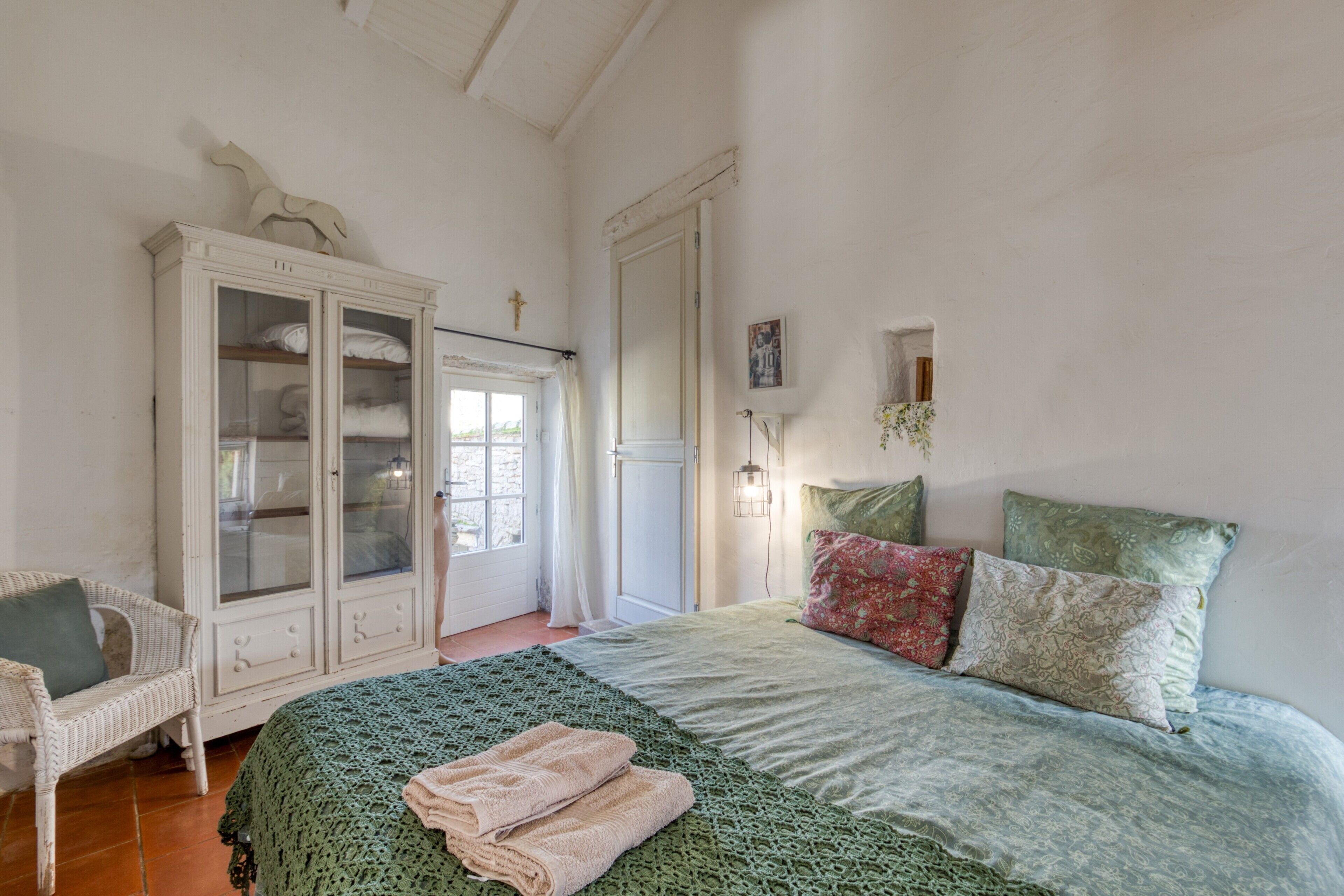 A bedroom with a bed, a wardrobe, a window, and a door.