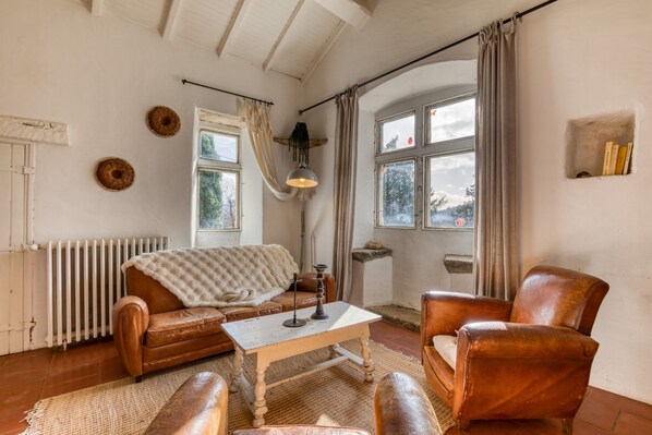 A cozy living room with a sofa, armchair, table, and a radiator.
