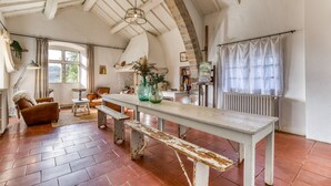 Um quarto amplo com teto alto, um banco de madeira, uma mesa e uma lareira.