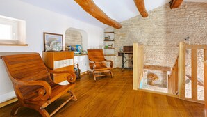 Ein Zimmer mit Holzboden, Steinwand und sichtbarem Holzbalken an der Decke.