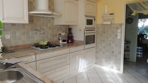 Une cuisine avec des meubles blancs, une cuisinière à gaz, un four et un four à micro-ondes.