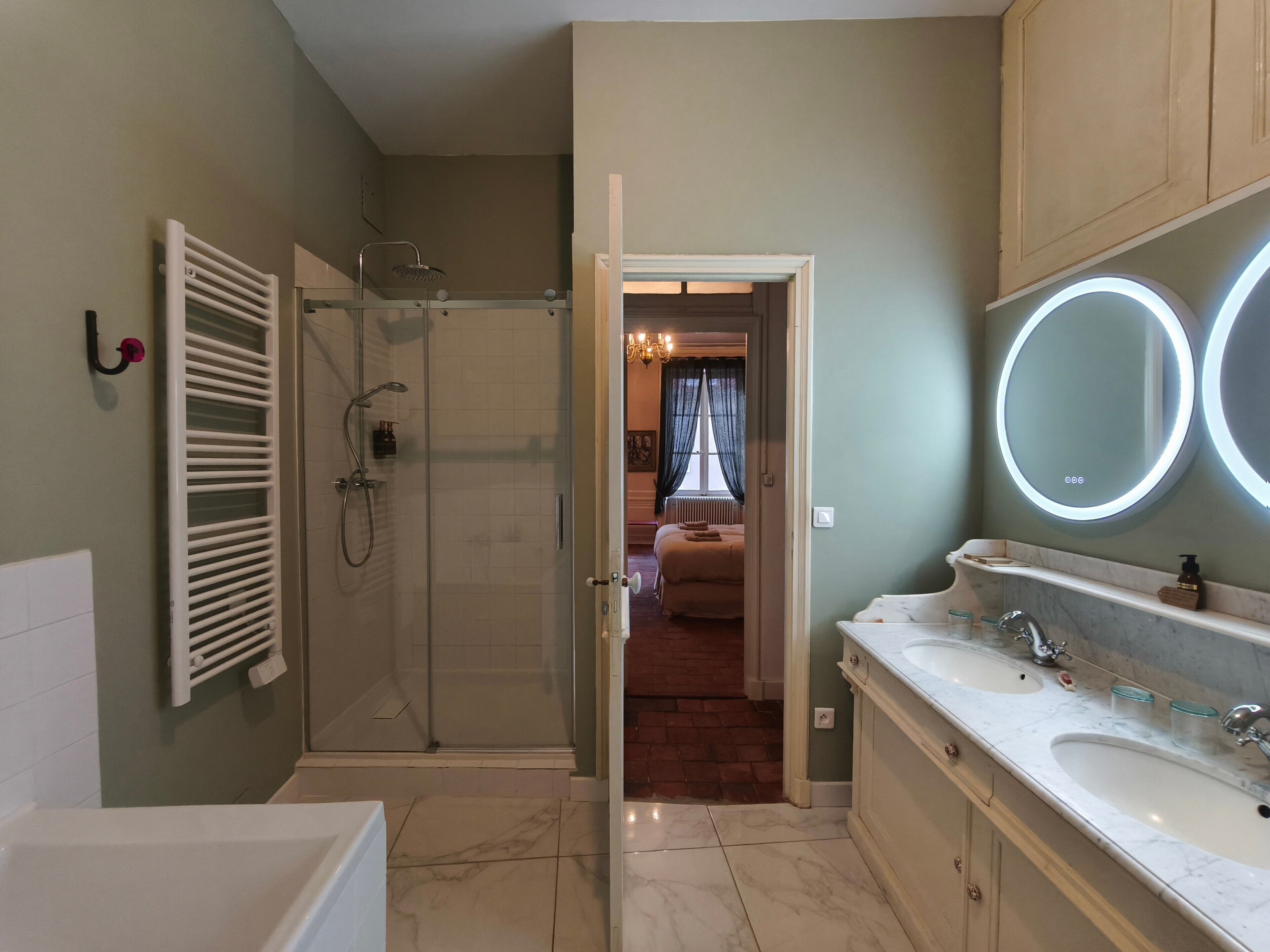 Une salle de bain avec une baignoire, une douche, un meuble-lavabo avec deux vasques et un miroir avec éclairage.