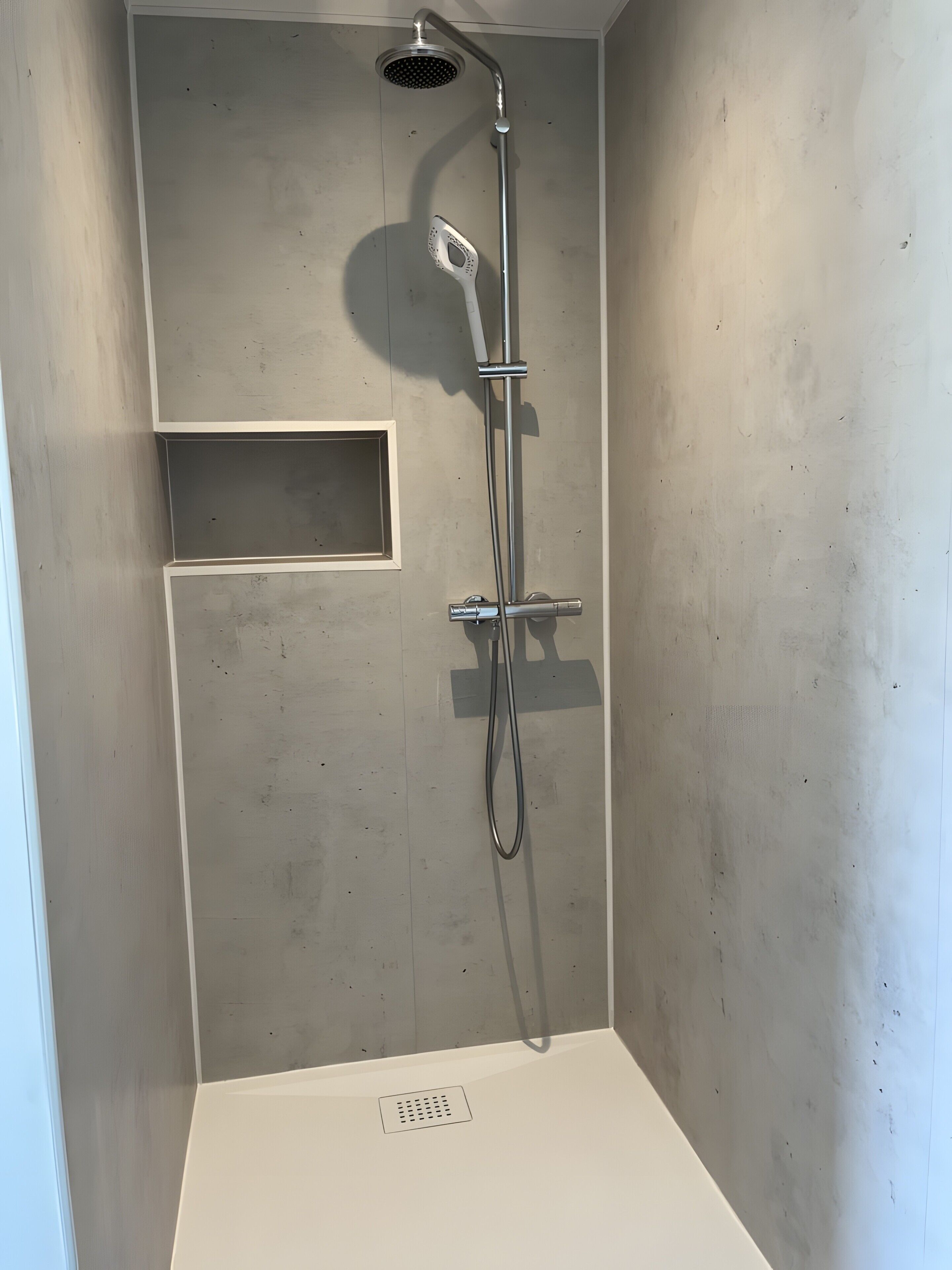 A shower with a handheld showerhead and a wall-mounted faucet.