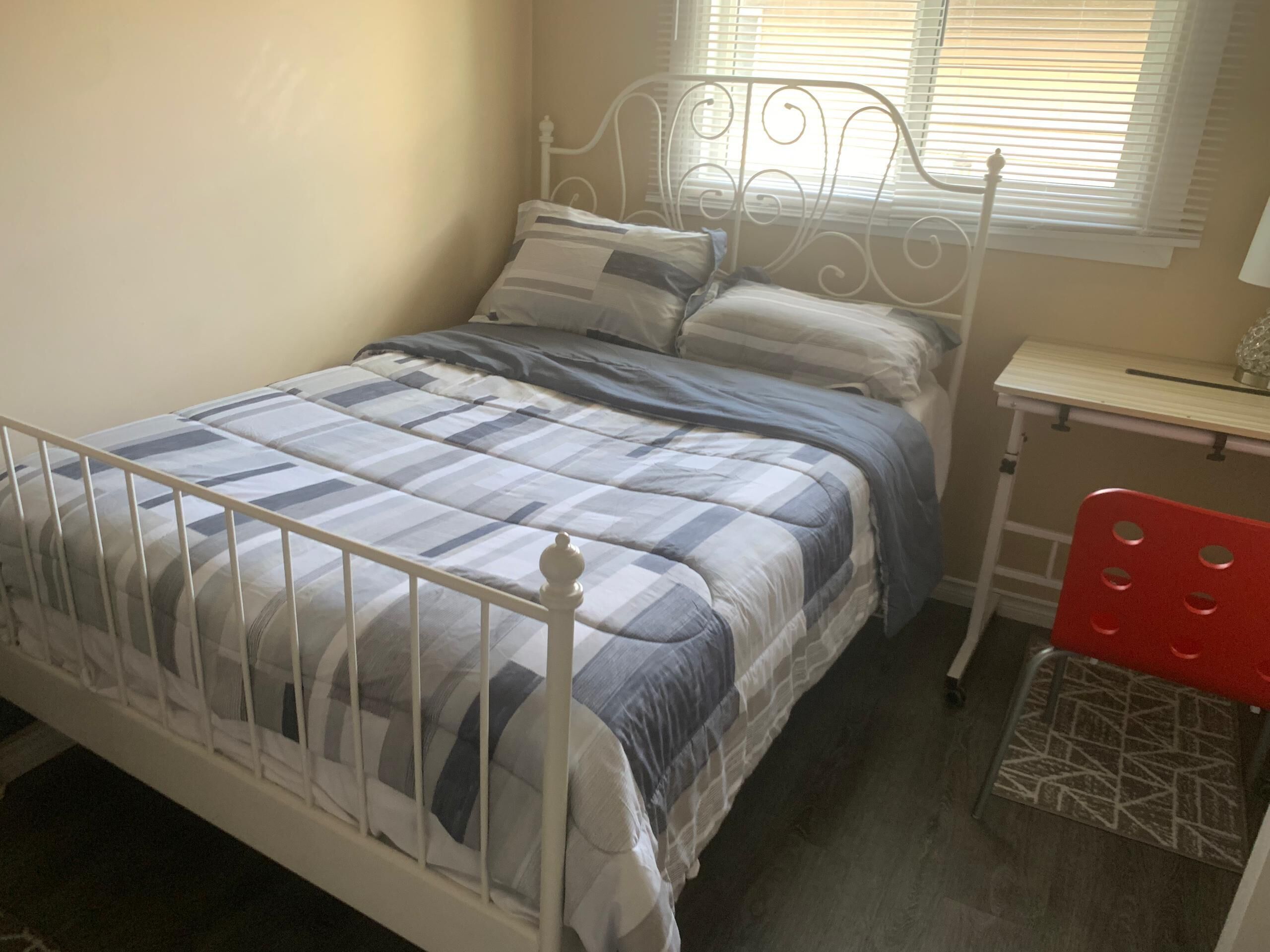 A bedroom with a bed, a desk, and a chair.