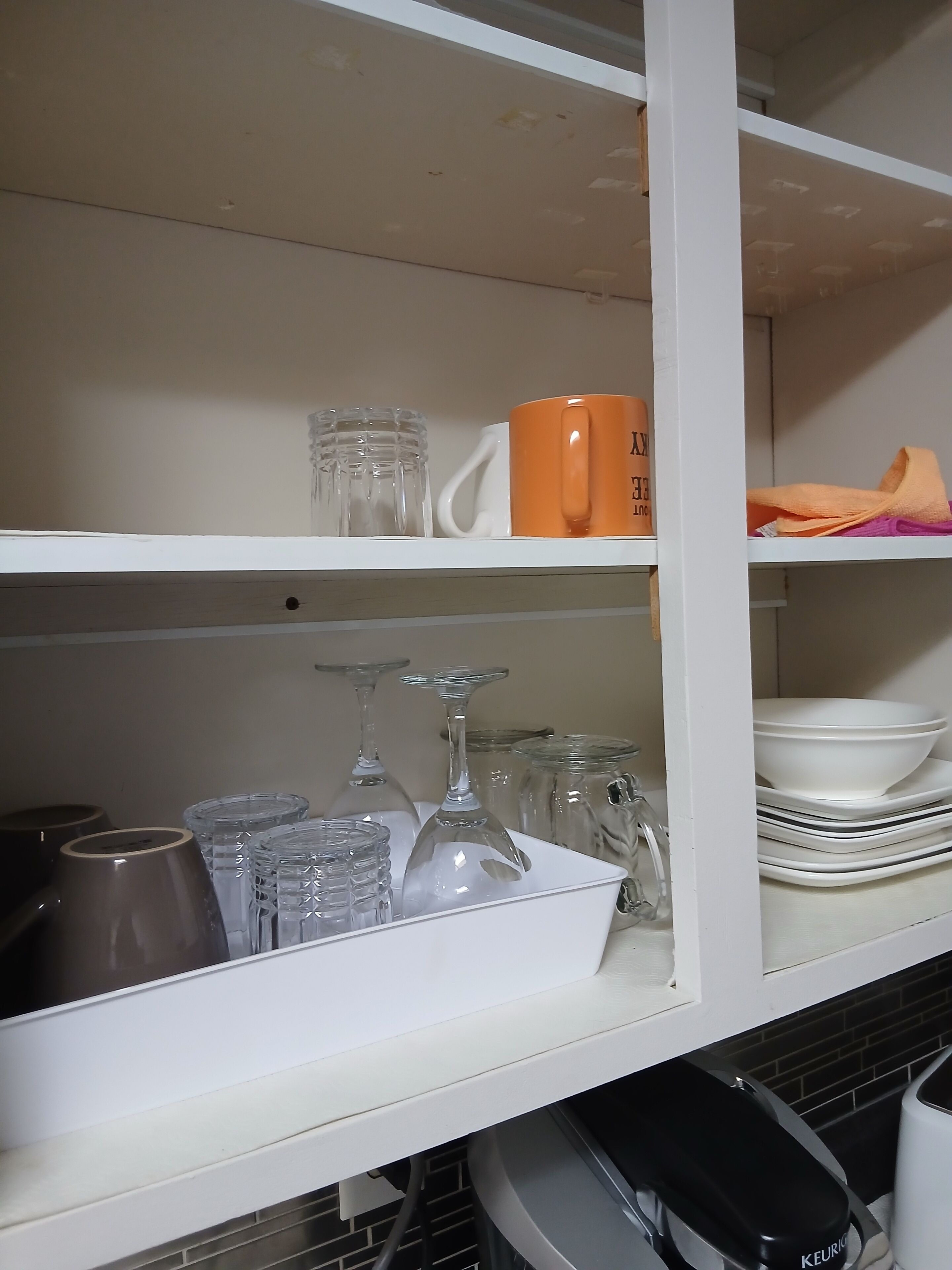 A kitchen with white shelves holding various glassware and dishes.