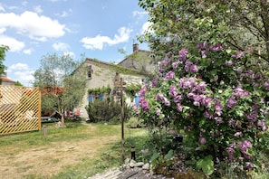 A rustic stone house with a garden featuring purple flowers and a wooden fence. - Gîte le Gué de Champagné, 10 min from St Jean d'Angély, 400 m from La Boutonne River (Torxé)
