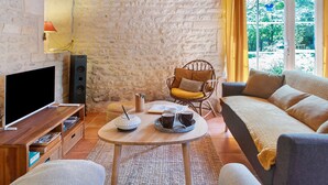 Una sala de estar acogedora con una pared de piedra, un televisor de pantalla plana, una mesa de centro de madera y un sofá cómodo.