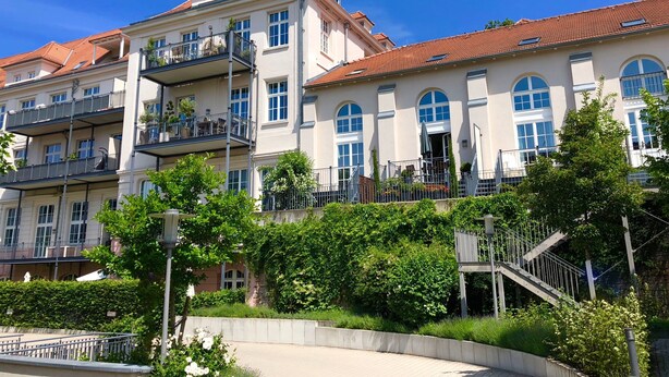 Un hôtel à plusieurs étages doté de balcons, d’un escalier central et d’une végétation luxuriante.