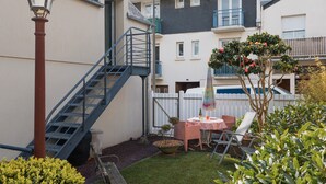 A residential building with a staircase, a small patio with a table and chairs, and a tree with flowers. - Les coccinelles, apartment for 2, 100 m from the port, Perros-Guirec (Perros Guirec)
