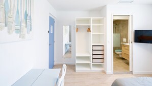 Een slaapkamer met een bed, een kledingkast, een spiegel en een televisie.