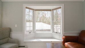 Ein Zimmer mit Erkerfenster, einer gepolsterten Sitzbank und zwei Stühlen.